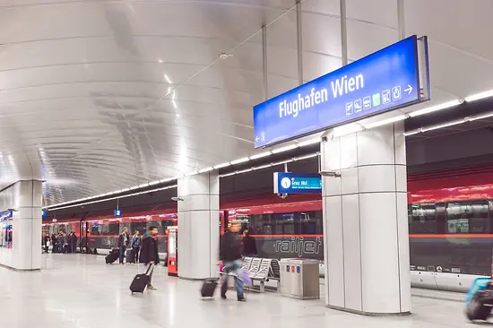 ÖBB Railjet en la estación del aeropuerto con viajeros en primer plano
